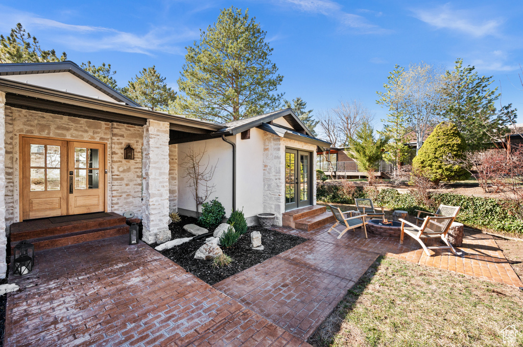 Exterior space with a patio area, french doors, stone siding, and stucco siding