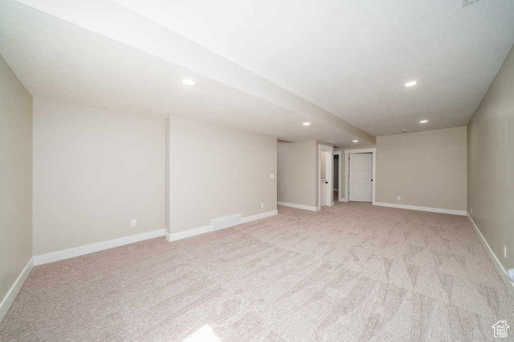 Finished below grade area featuring light colored carpet, visible vents, and recessed lighting
