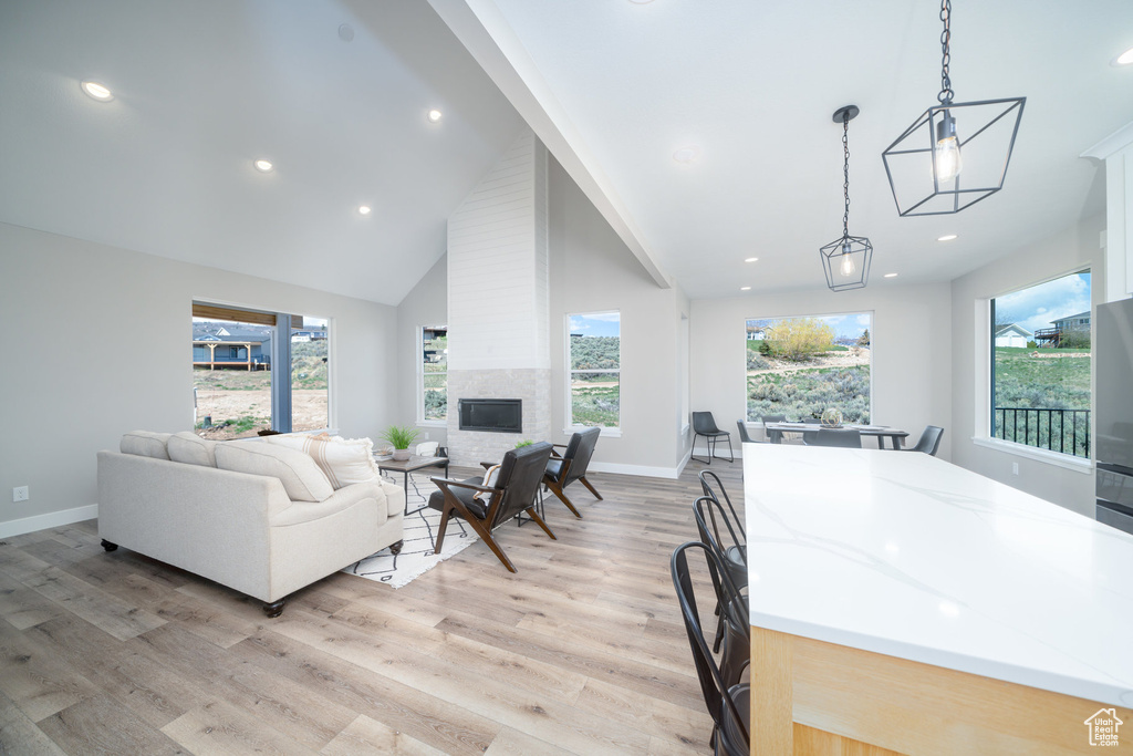Living area with baseboards, light wood-type flooring, and high vaulted ceiling