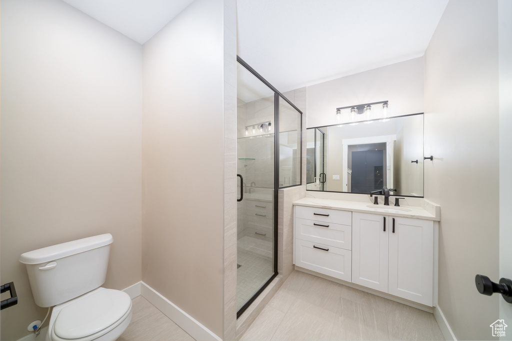 Bathroom with a stall shower, vanity, toilet, and baseboards