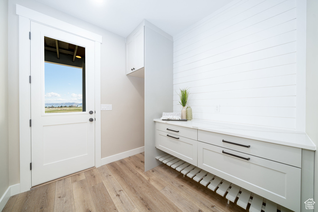 Doorway with baseboards and light wood-style flooring