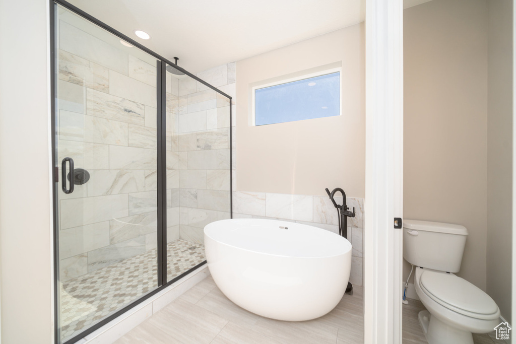 Full bath featuring a stall shower, tile walls, a freestanding bath, and toilet