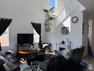Living room featuring wood finished floors, a towering ceiling, a fireplace, and a wealth of natural light