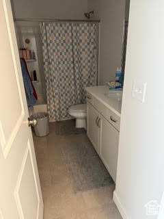 Bathroom with vanity, a shower with shower curtain, and toilet