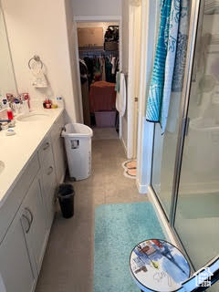 Full bathroom with double vanity, a stall shower, and a sink