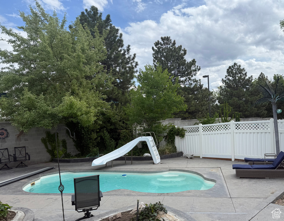View of pool with a patio, a fenced backyard, a water slide, and a fenced in pool