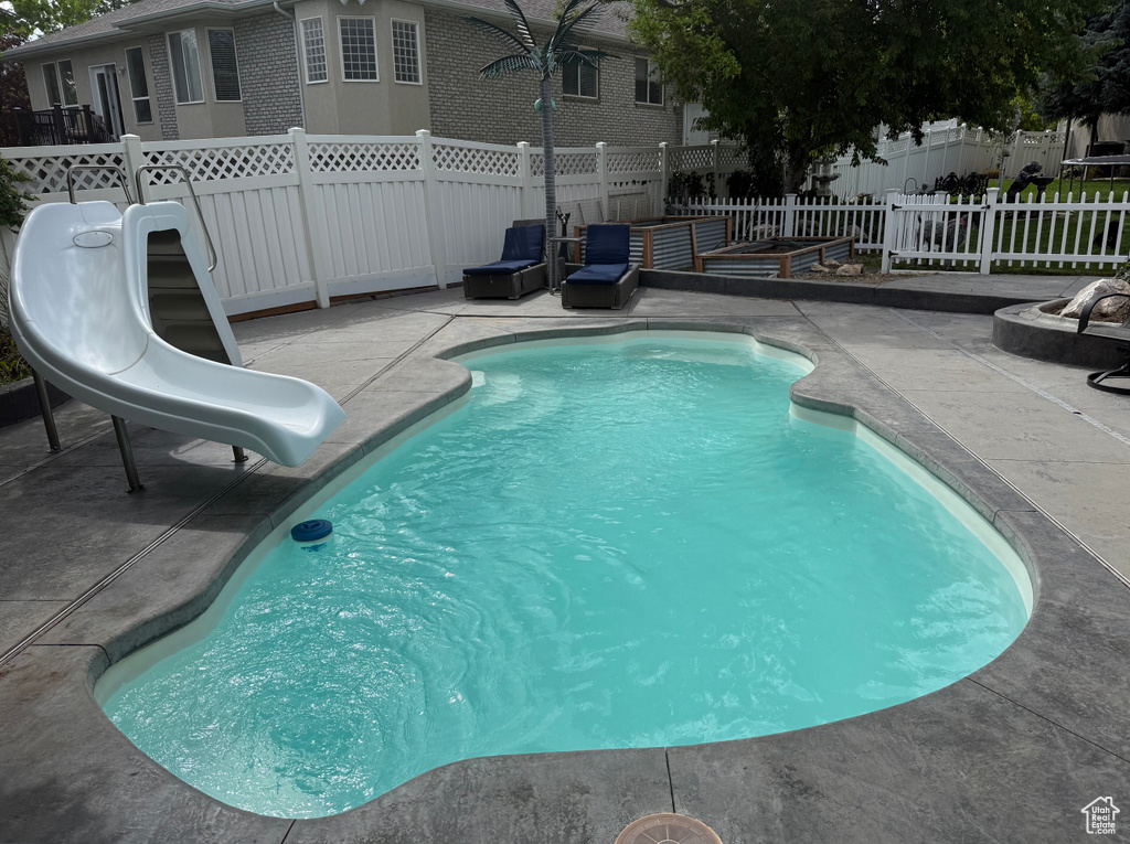 View of pool with a patio, a water slide, a fenced backyard, and a fenced in pool
