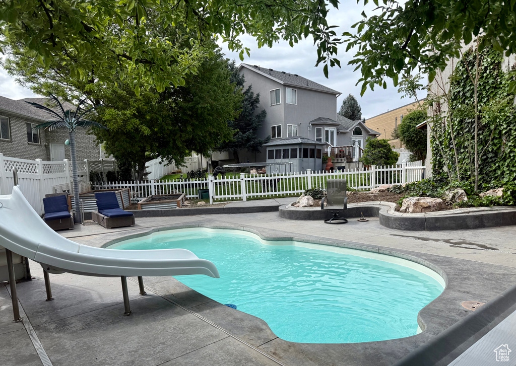 View of swimming pool with a fenced in pool, a water slide, a fenced backyard, and a patio