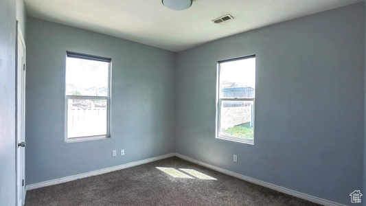 Spare room with dark carpet and baseboards