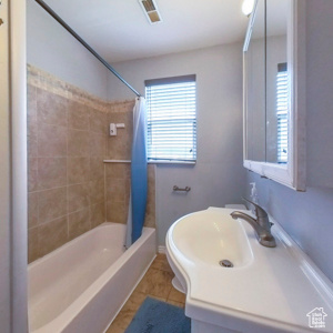 Full bathroom with shower / tub combo, vanity, tile patterned flooring, and baseboards