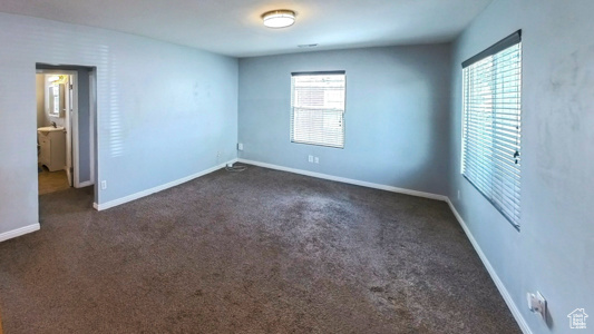 Unfurnished room featuring dark carpet and baseboards