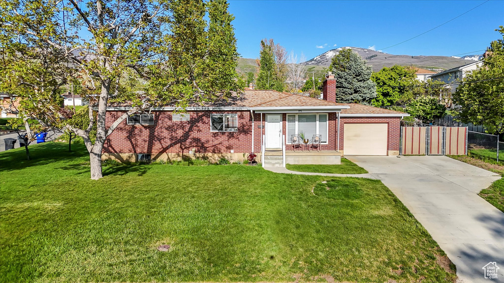 Ranch-style house featuring a front lawn, fence, brick siding, concrete driveway, and an attached garage