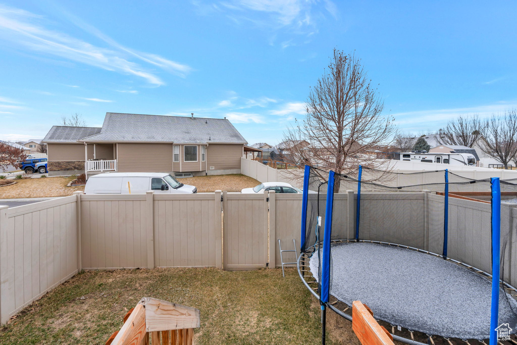 View of yard featuring a trampoline, a fenced backyard, and a residential view