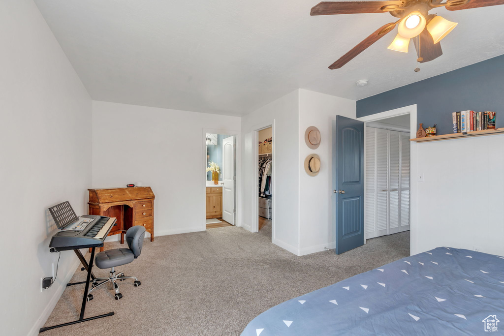 Carpeted bedroom with a ceiling fan, baseboards, a closet, ensuite bathroom, and a walk in closet