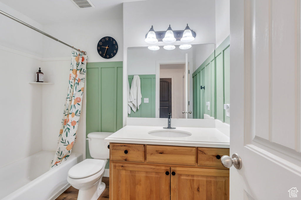 Bathroom featuring visible vents, shower / bath combo with shower curtain, toilet, and vanity