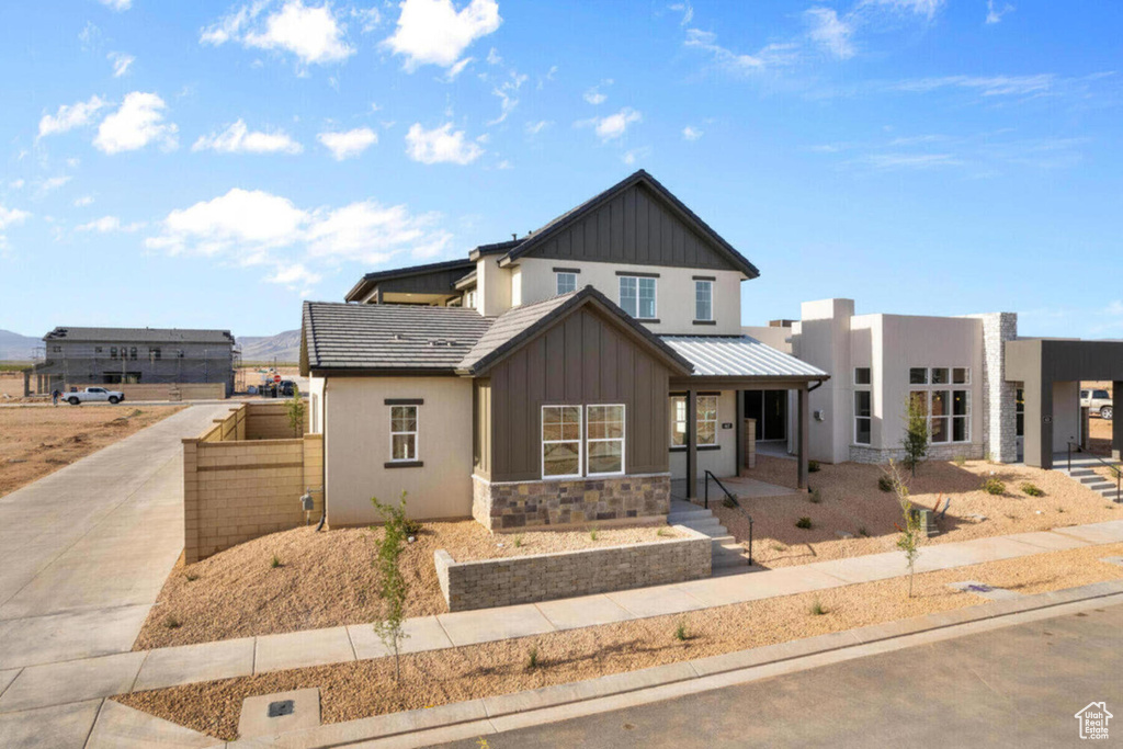 View of front of home featuring driveway, stone siding, stucco siding, board and batten siding, and a porch