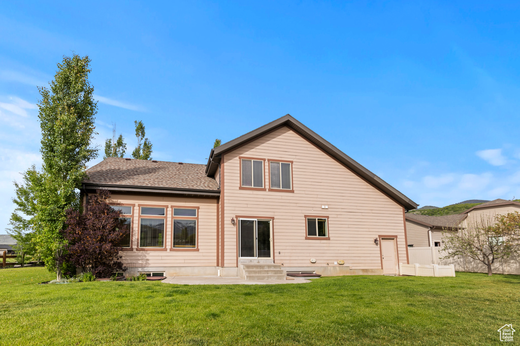 Rear view of property featuring a yard, entry steps, a patio, and a shingled roof