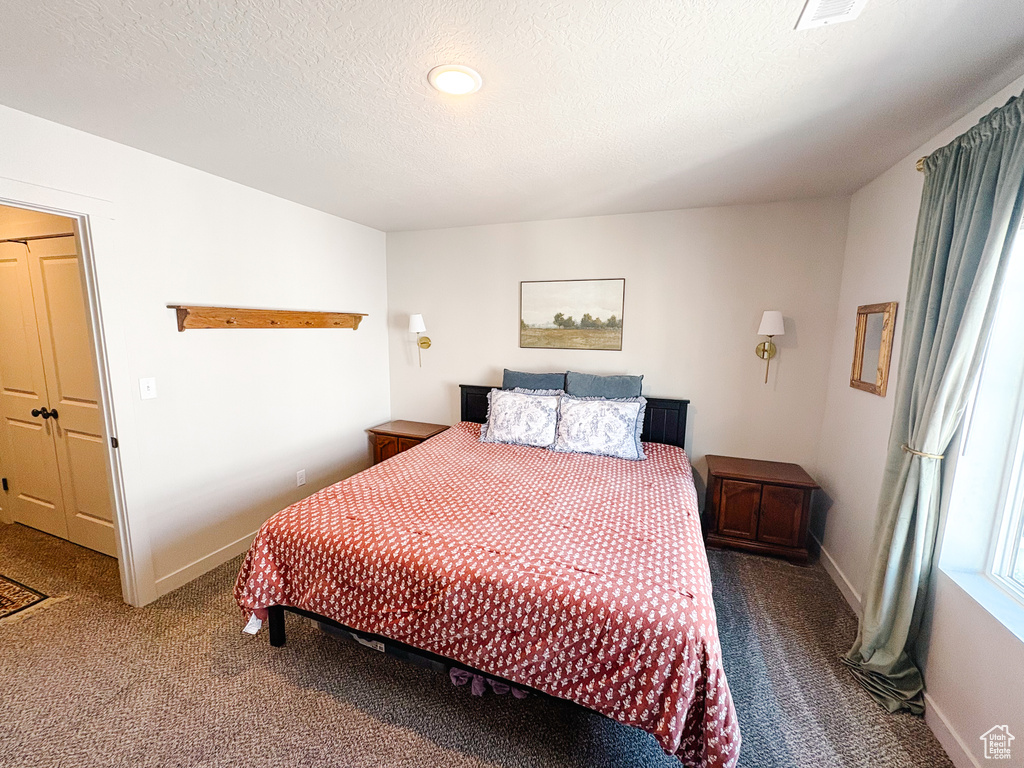 Carpeted bedroom featuring baseboards and a textured ceiling