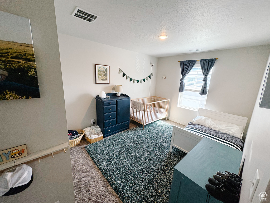 Carpeted bedroom with visible vents and a textured ceiling