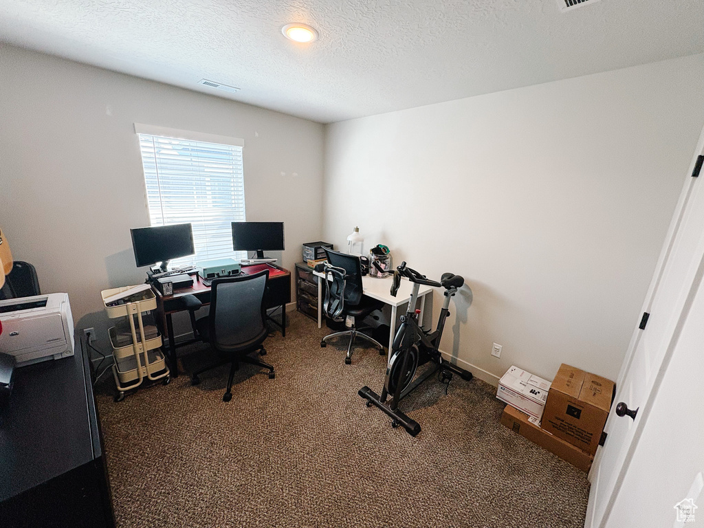 Home office with visible vents, baseboards, a textured ceiling, and carpet flooring
