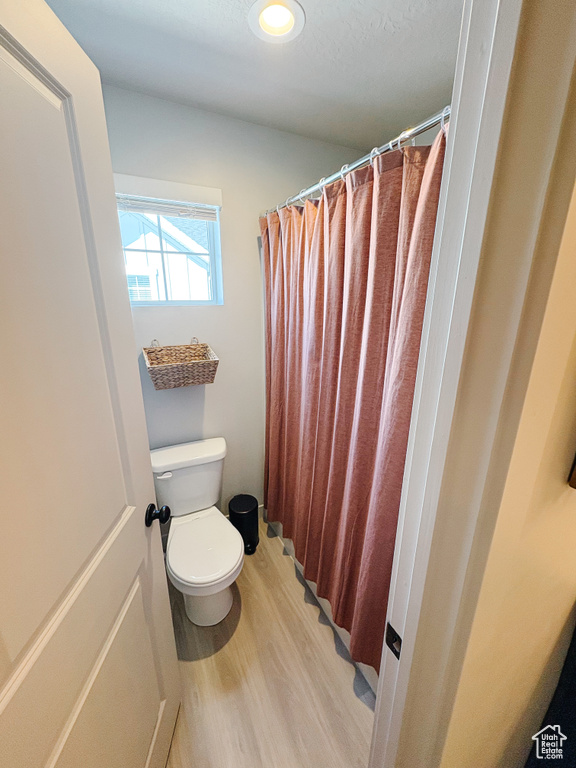 Full bathroom featuring recessed lighting, curtained shower, toilet, and wood finished floors