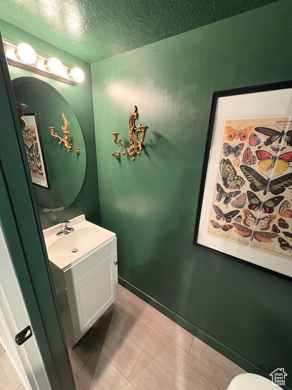 Half bathroom featuring vanity and a textured ceiling