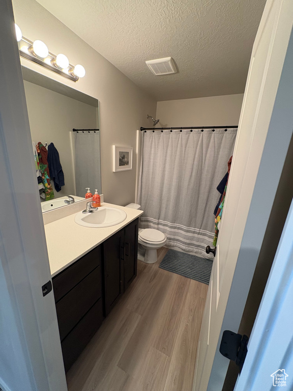 Bathroom with visible vents, toilet, a textured ceiling, wood finished floors, and vanity