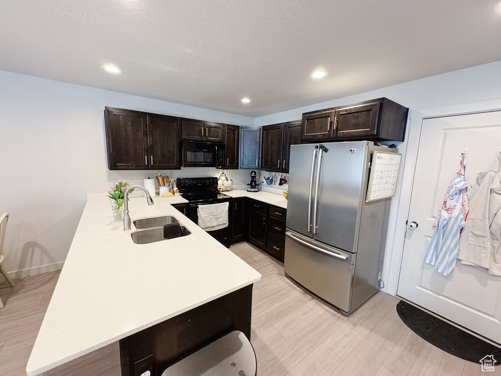 Kitchen featuring black appliances, a sink, recessed lighting, dark brown cabinetry, and light countertops