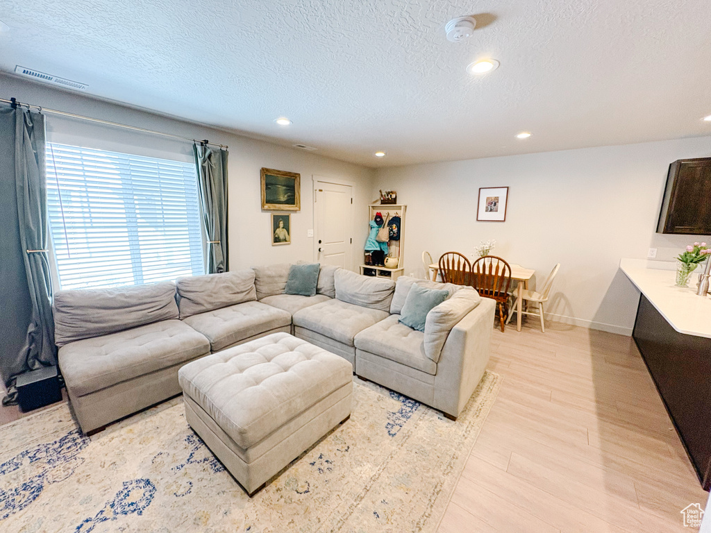 Living area featuring visible vents, light wood-style flooring, a textured ceiling, recessed lighting, and baseboards