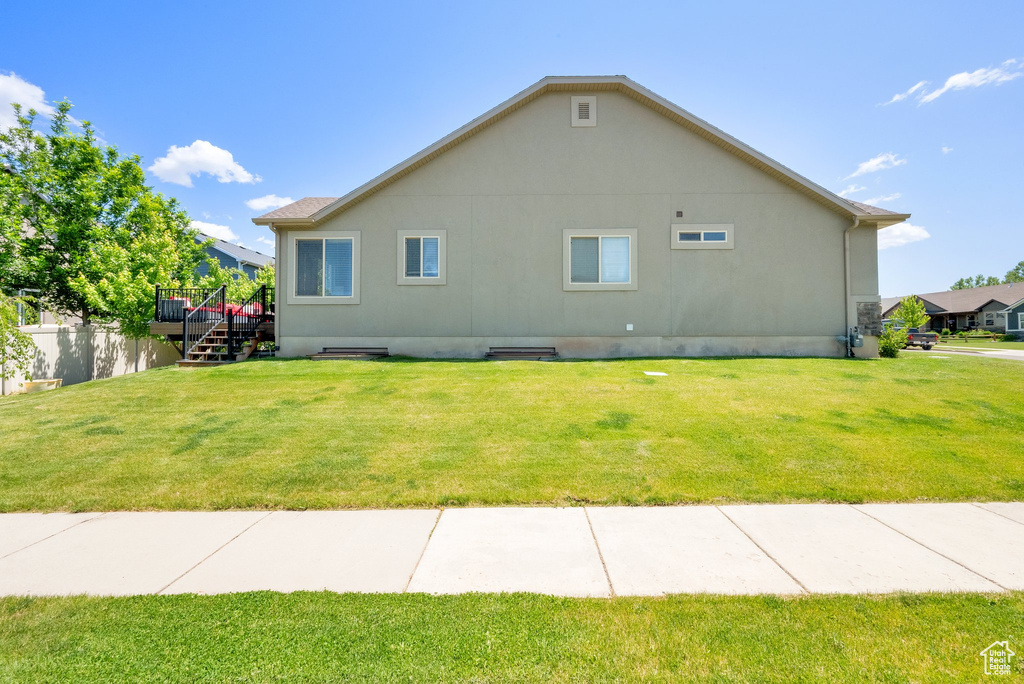 View of side of property featuring a deck, a lawn, and stairway