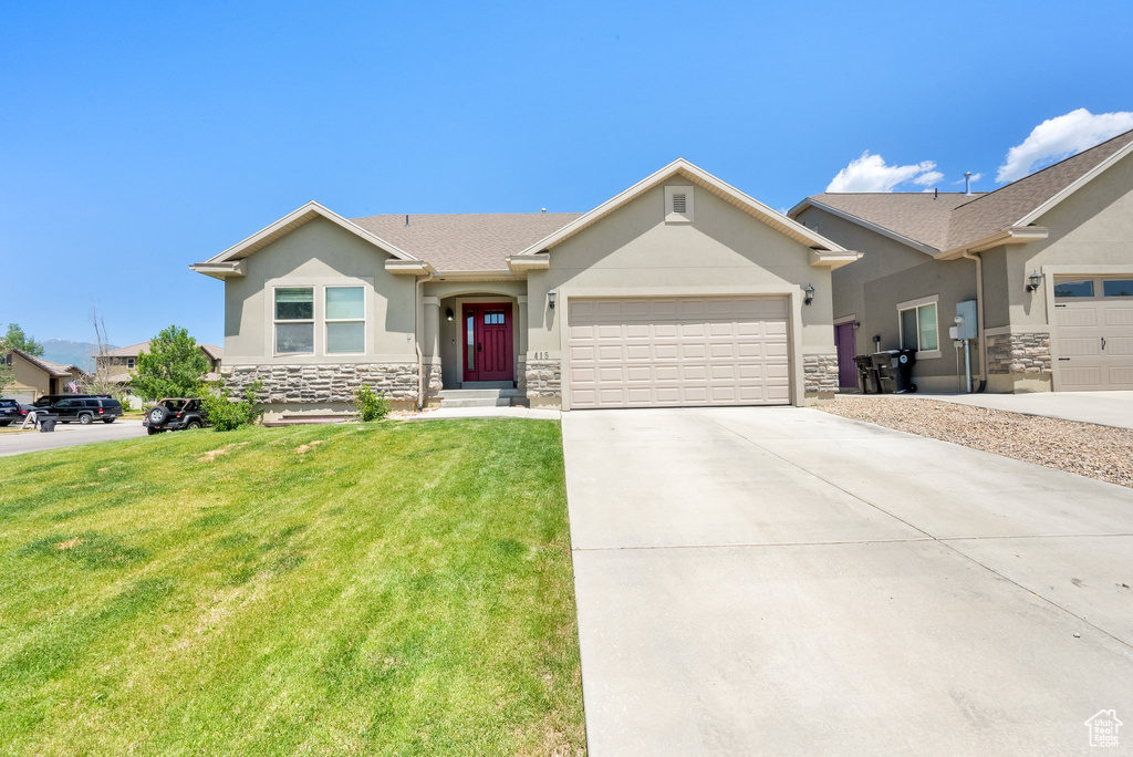 Ranch-style house featuring stone siding, stucco siding, a garage, and a front yard