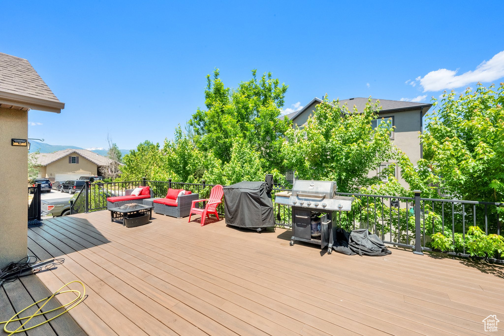 Wooden deck with an outdoor living space with a fire pit and a grill