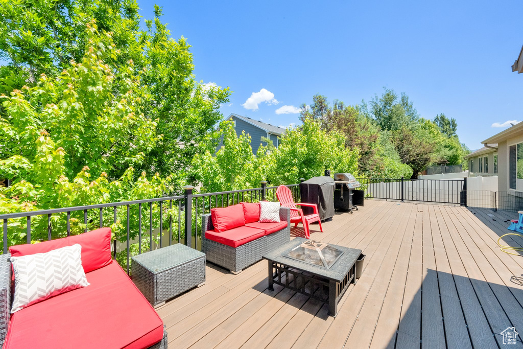 Wooden deck featuring an outdoor living space with a fire pit and area for grilling