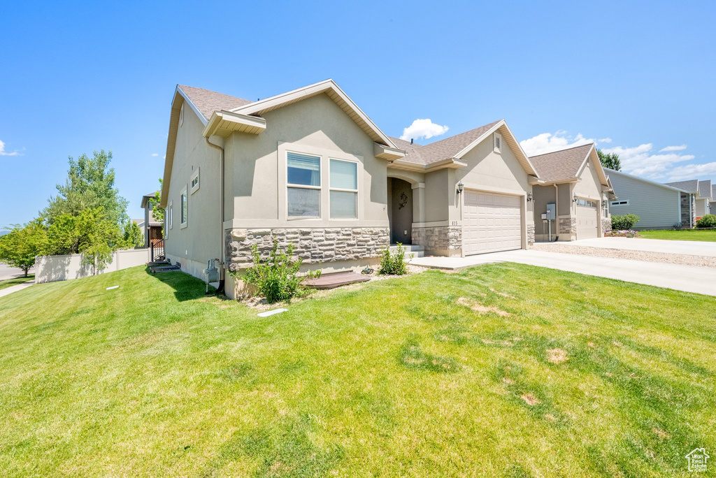 View of front of property with a garage, driveway, stone siding, and stucco siding