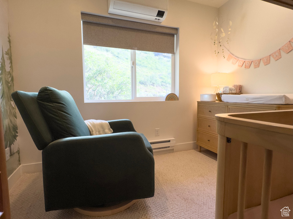 Living area with baseboards, baseboard heating, carpet flooring, and a wall unit AC