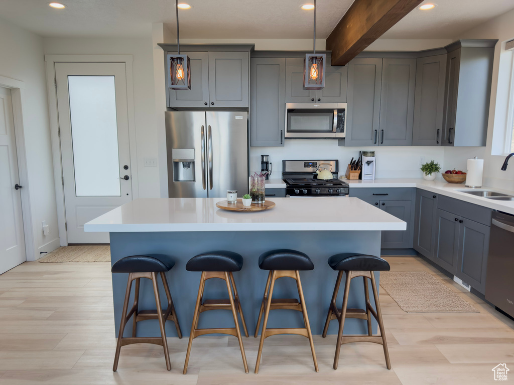 Kitchen featuring a center island, a breakfast bar area, light countertops, stainless steel appliances, and a sink