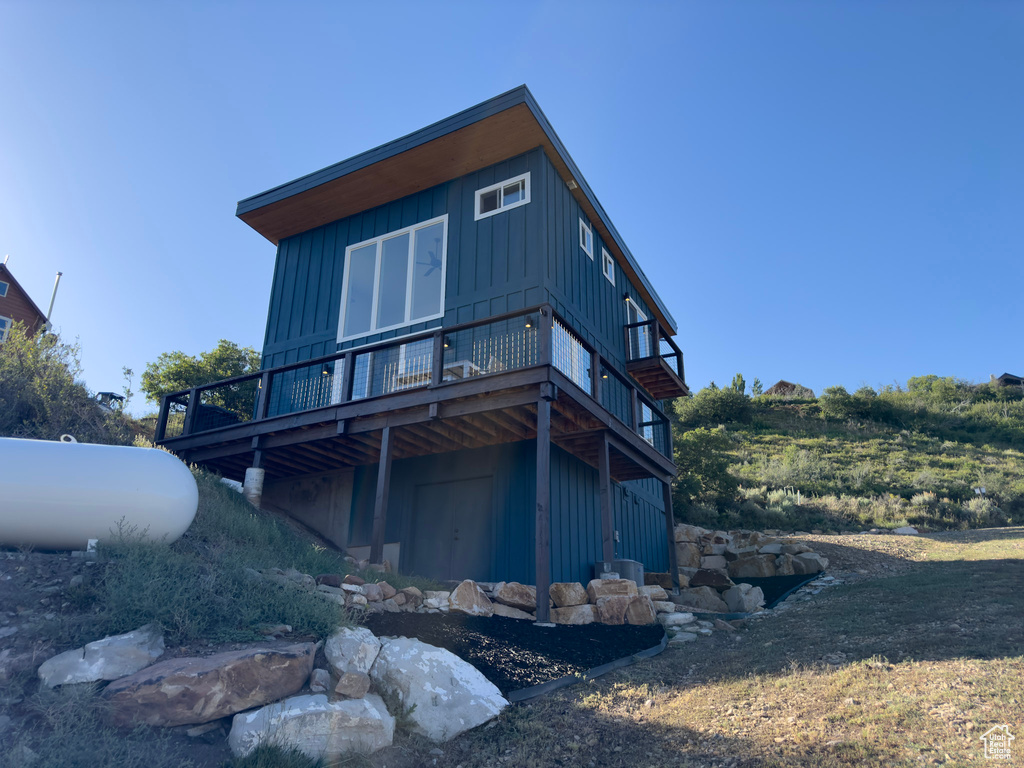Rear view of property with board and batten siding and a wooden deck