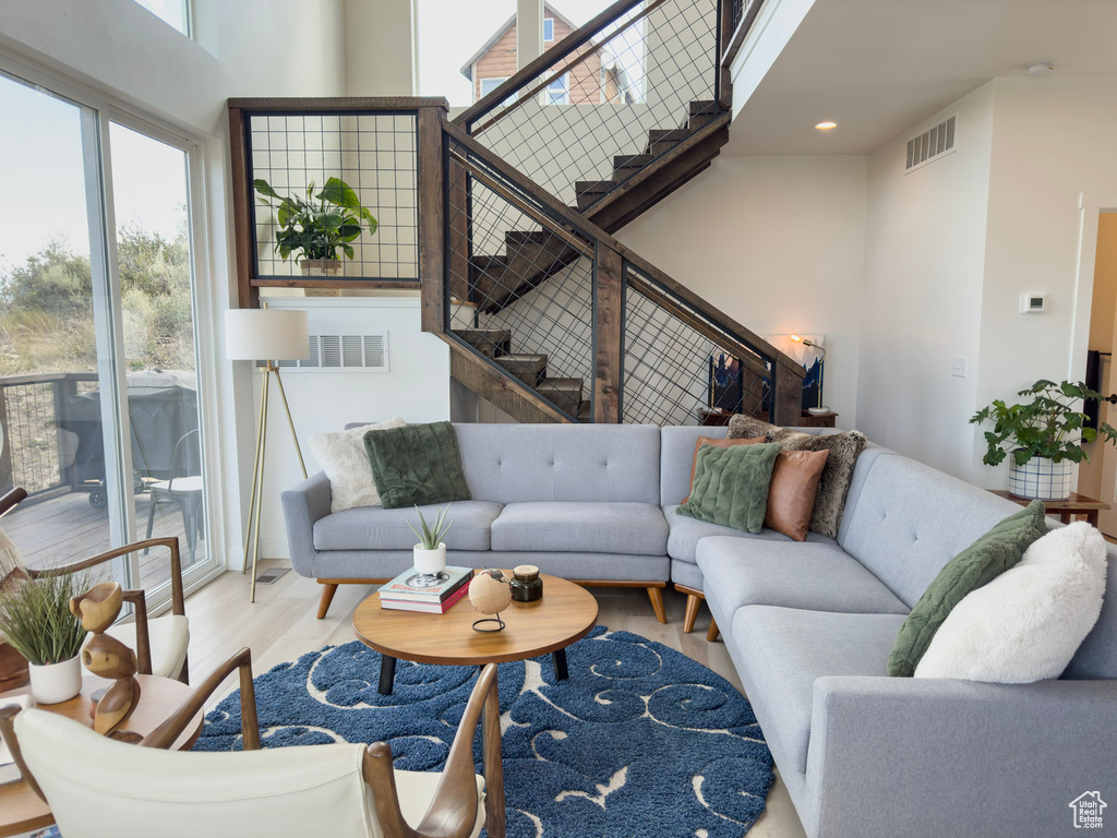 Living area with stairs, wood finished floors, visible vents, and a towering ceiling