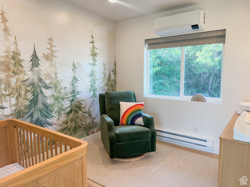 Carpeted bedroom with a baseboard heating unit, a wall unit AC, and a crib