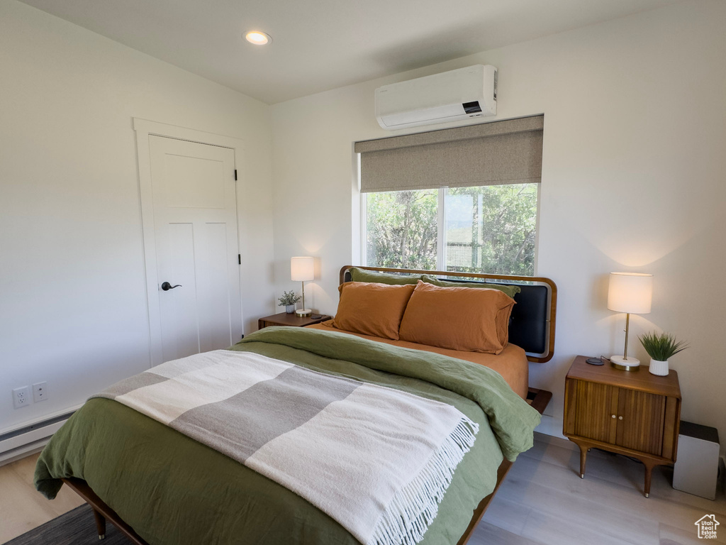 Bedroom featuring recessed lighting, an AC wall unit, and light wood finished floors