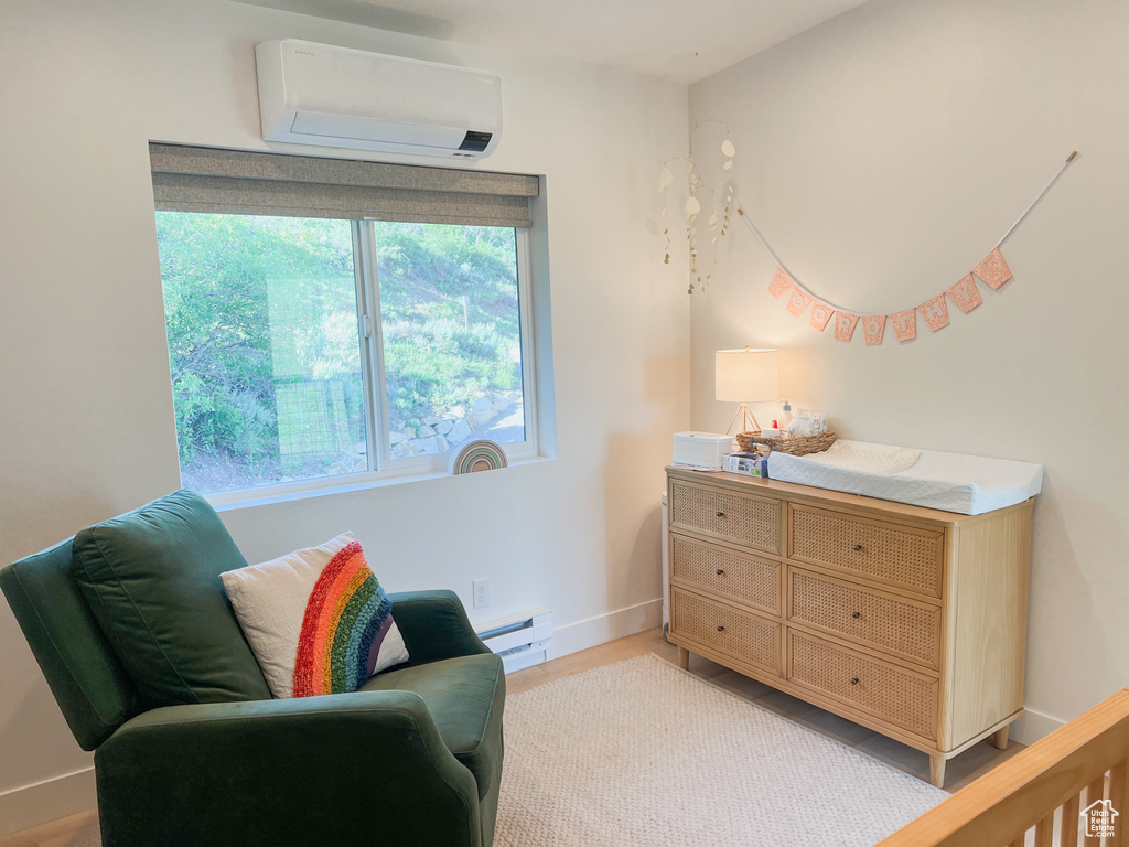Living area featuring an AC wall unit, a baseboard heating unit, and light wood-style flooring