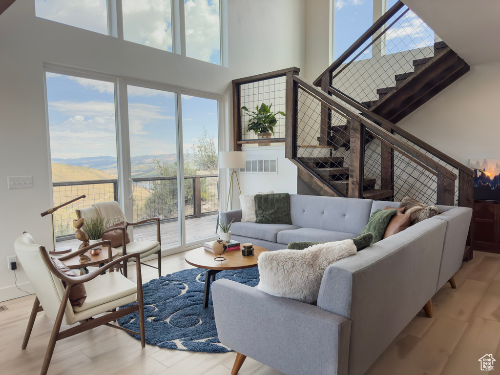 Living area with visible vents, a mountain view, light wood-type flooring, and a towering ceiling
