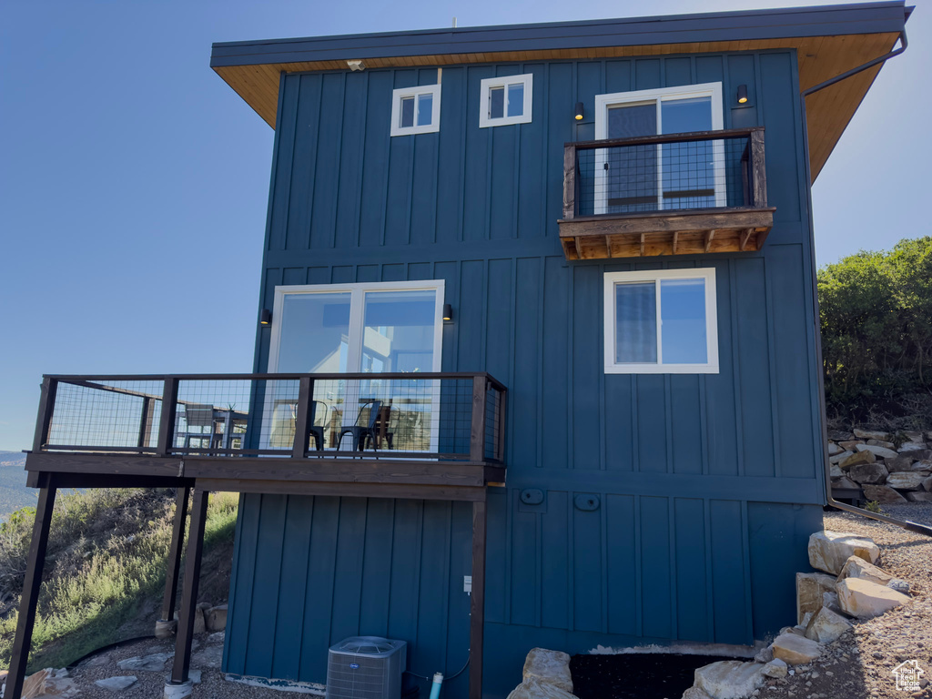 Back of property with board and batten siding, central AC, and a balcony
