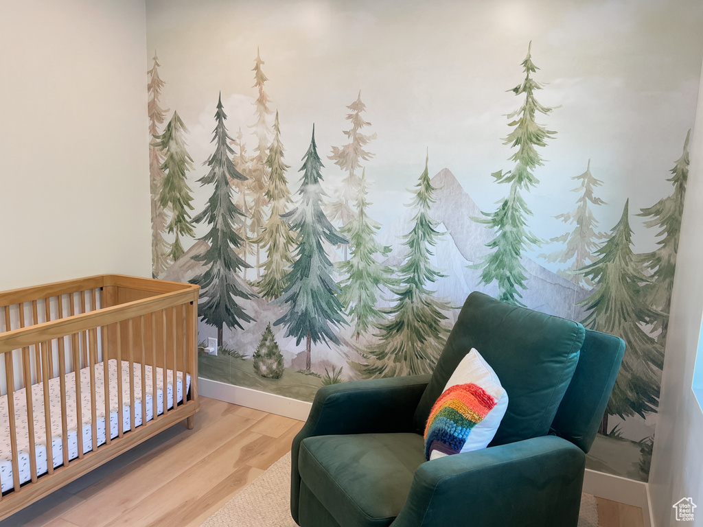 Bedroom with wood finished floors and a nursery area