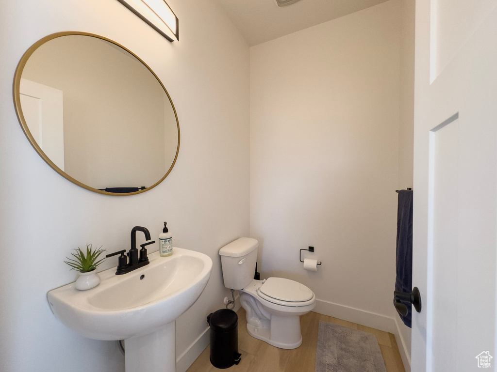 Bathroom with toilet, wood finished floors, baseboards, and a sink