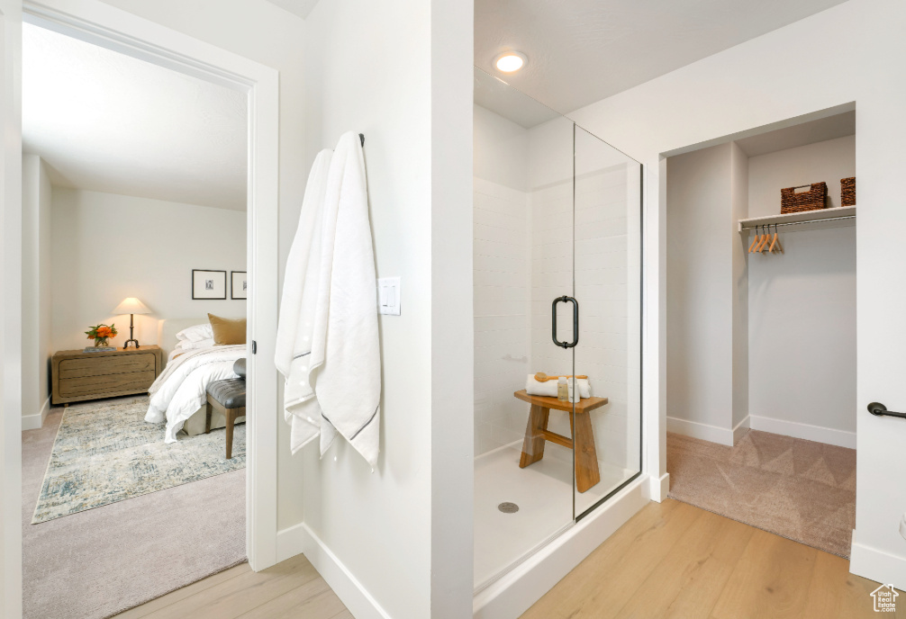 Ensuite bathroom featuring a shower stall, connected bathroom, baseboards, and wood finished floors