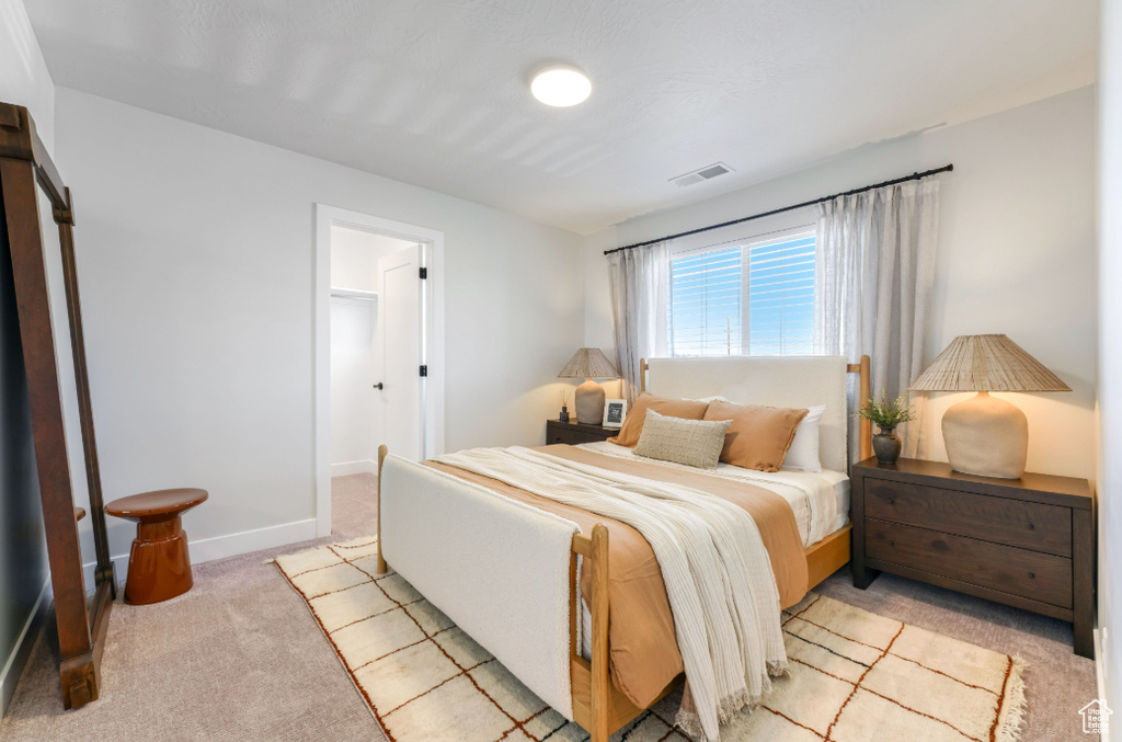 Bedroom with light carpet, visible vents, and baseboards