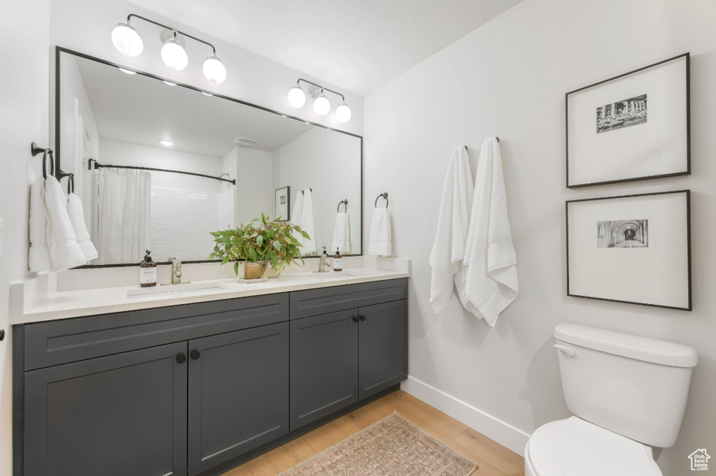 Bathroom with a sink, baseboards, toilet, and wood finished floors