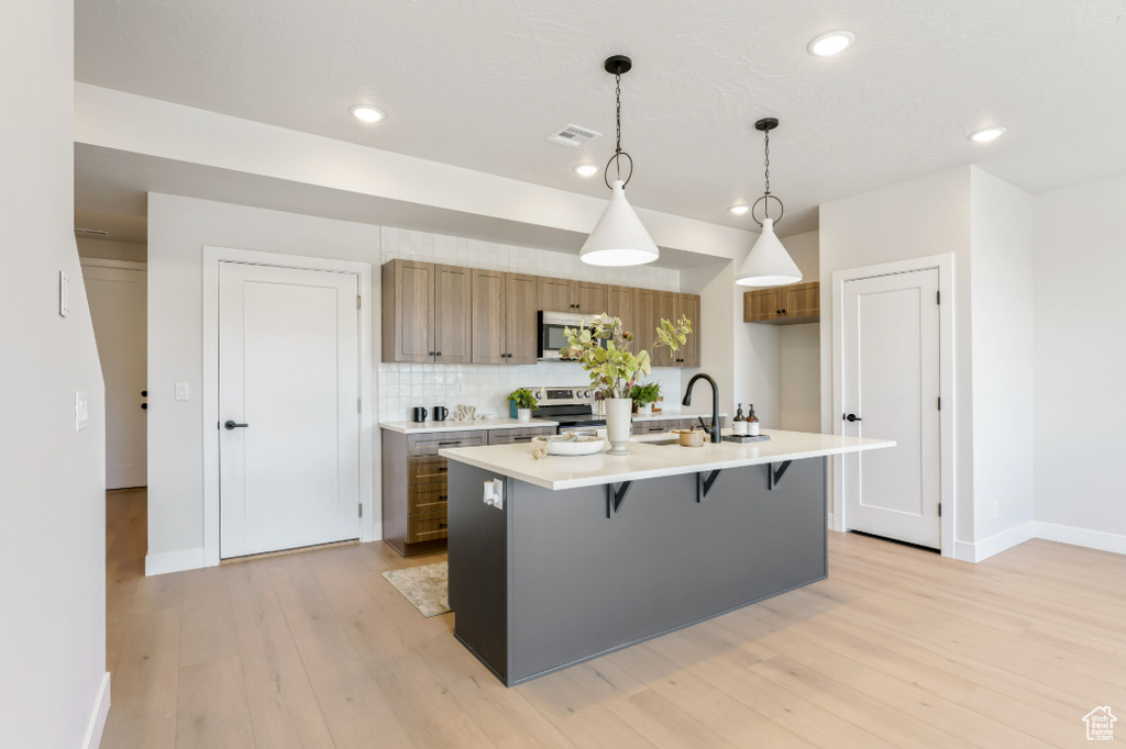Kitchen with visible vents, light wood finished floors, appliances with stainless steel finishes, and light countertops