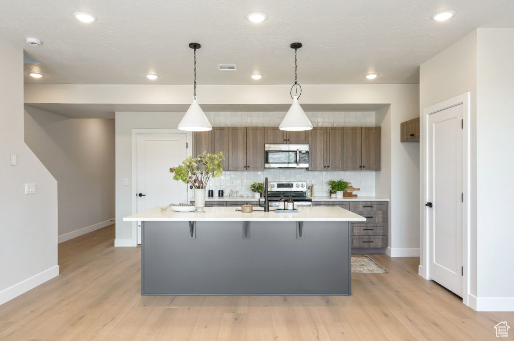 Kitchen featuring stainless steel appliances, visible vents, decorative backsplash, and light countertops
